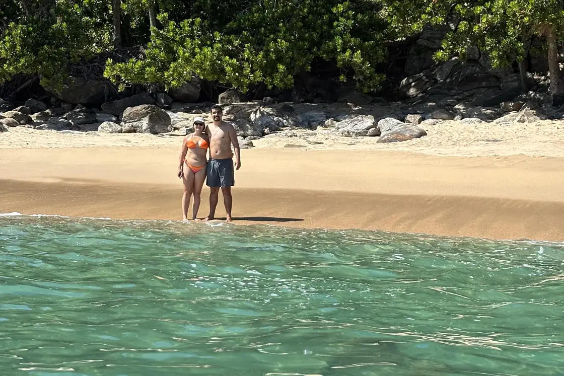 Casal sozinho na beira da praia, visto de dentro da água.