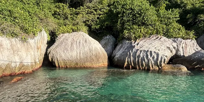 Pedras claras e uma piscina natural de água esverdeada na beira da ilha.
